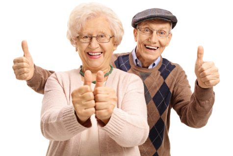 Overjoyed seniors holding their thumbs up isolated on white background